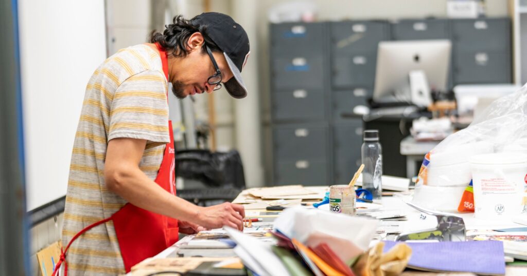 A person wearing an apron creates art.