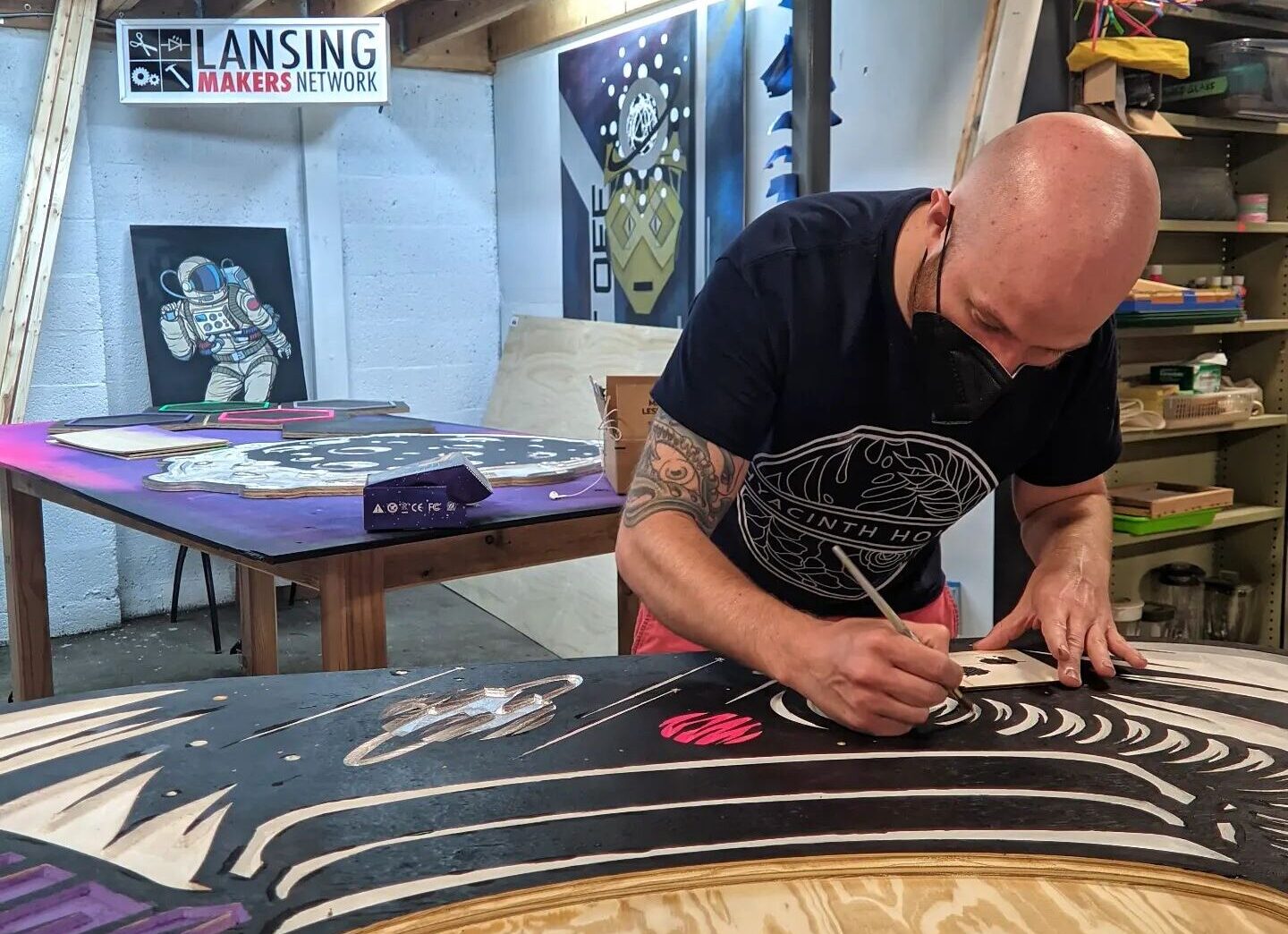 A person with light skin creates a large visual artwork on a table.