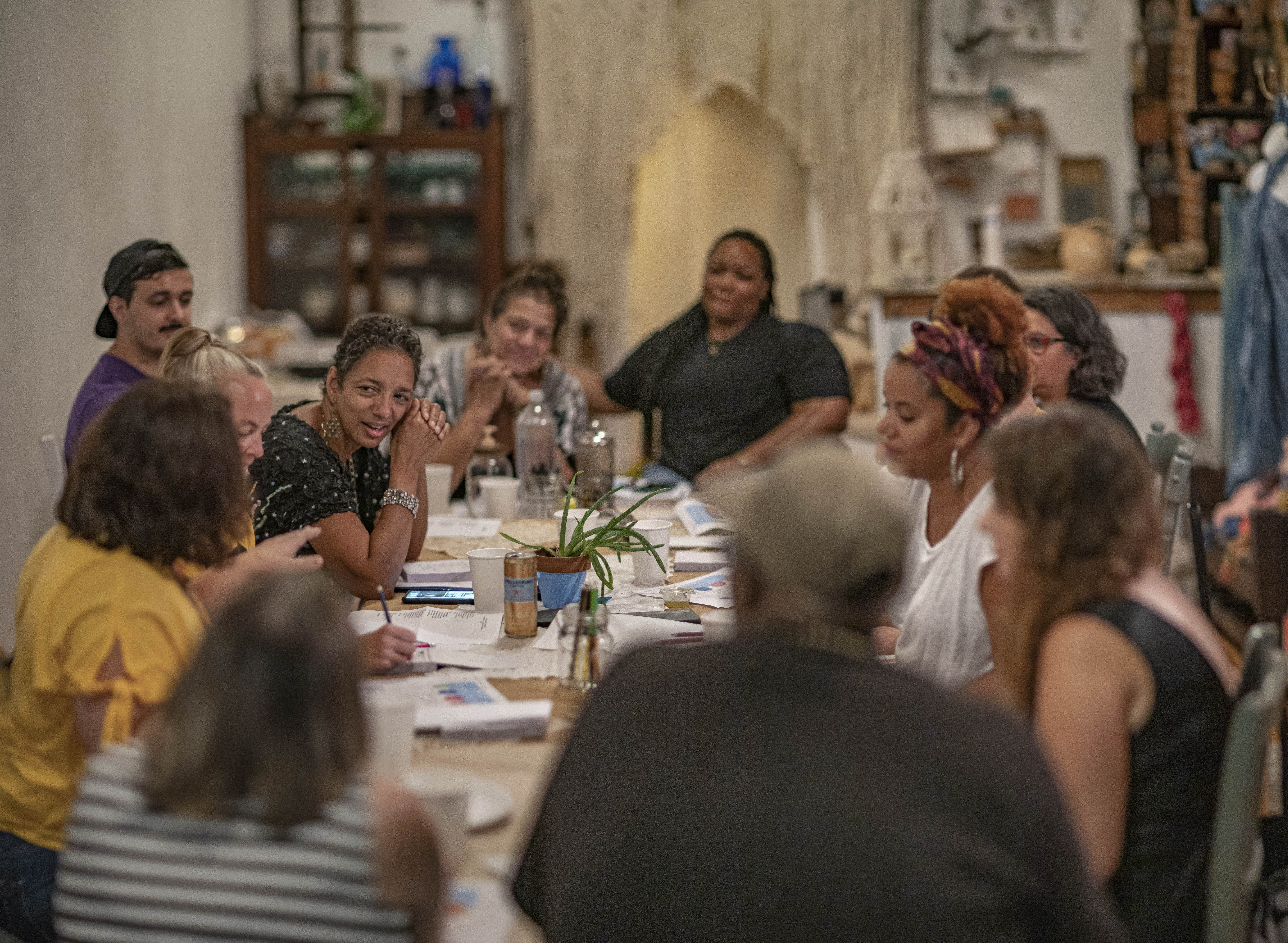 A group of people seated around a table, engaged in discussion.