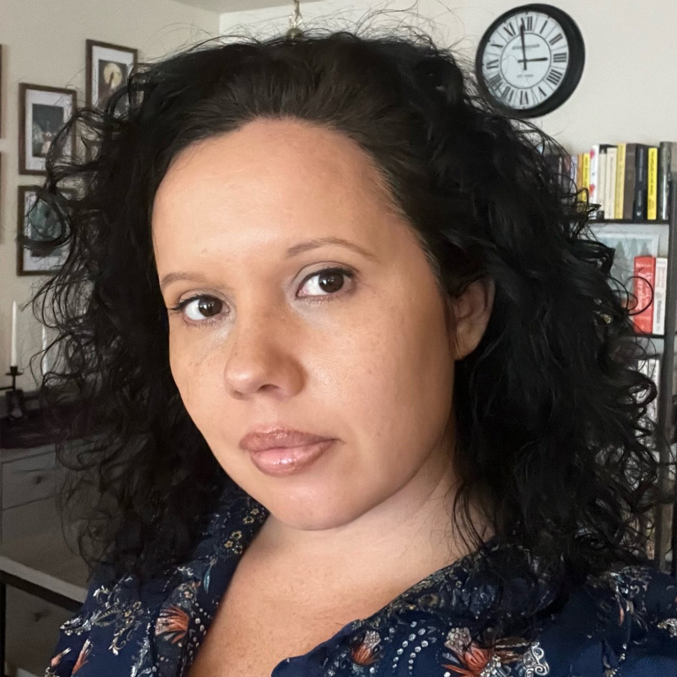 Headshot of a person of medium-light skin tone with long black hair, wearing a floral blouse.