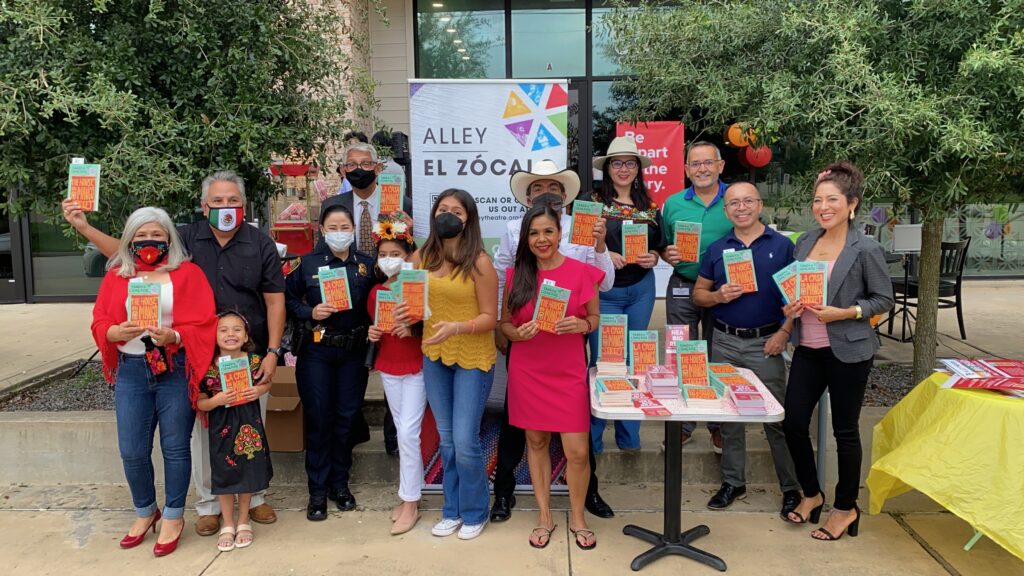 A group of smiling people holding up copies of Sandra Cisneros's novel, "The House on Mango Street."