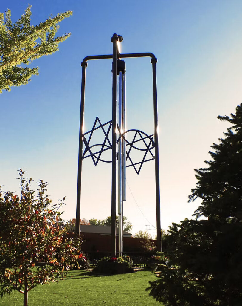 A large structure with two stars and two fish symbols amid trees on a lawn.