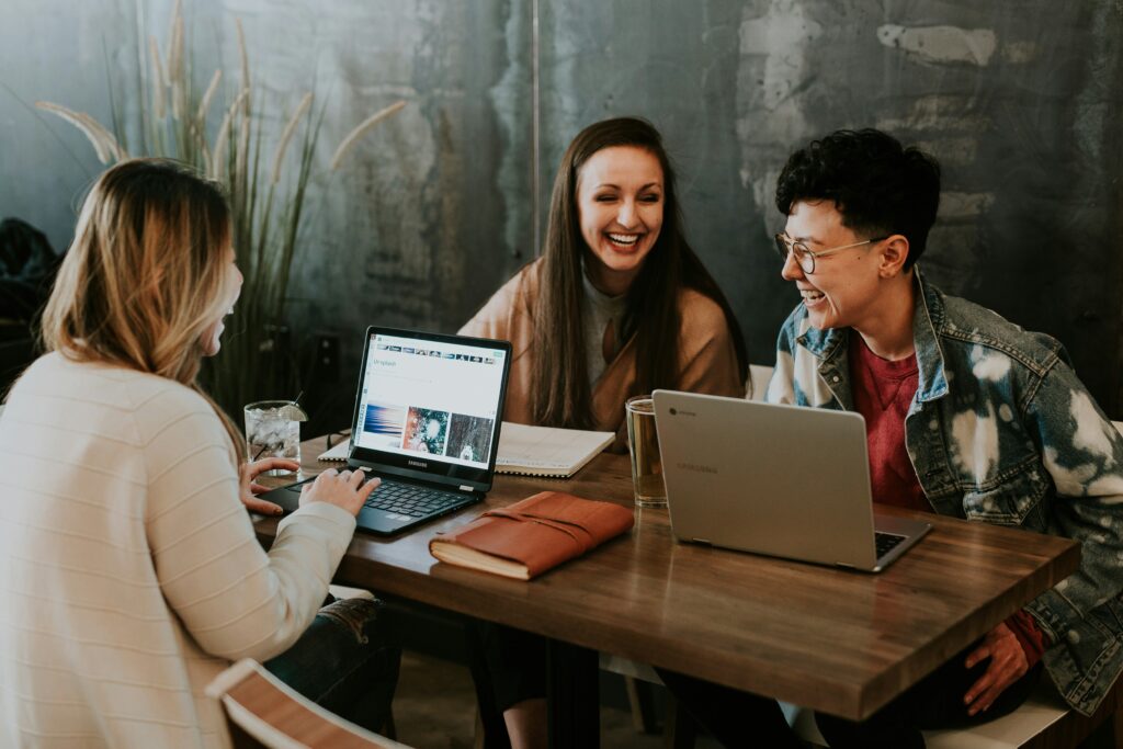 Three young people sitting around a table with laptops in front of them.