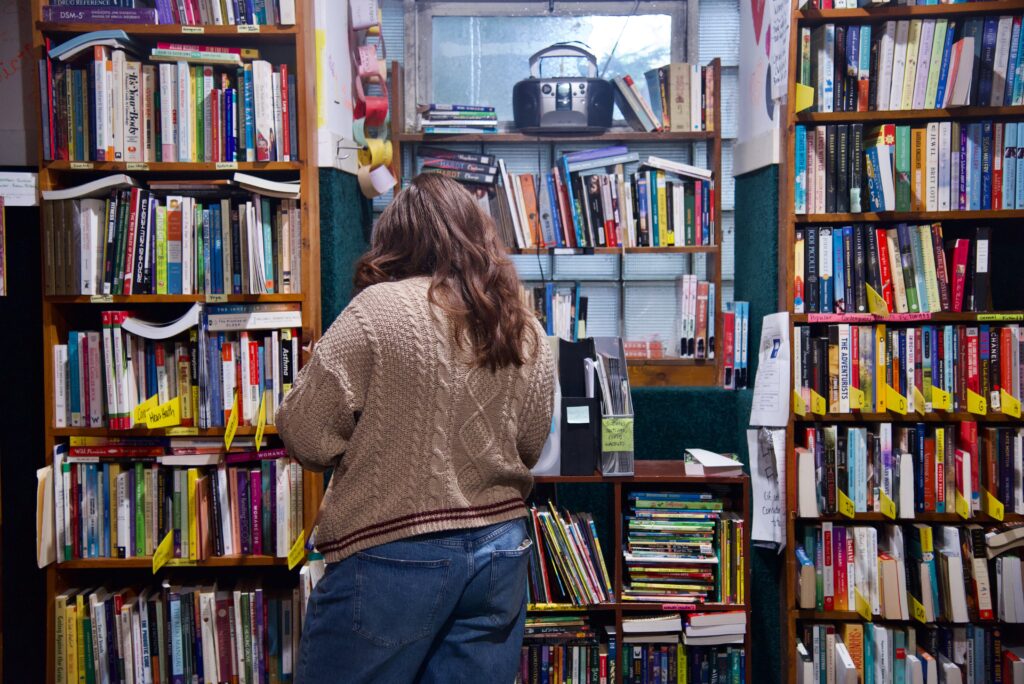 Person standing in a room facing walls of bookshelves.