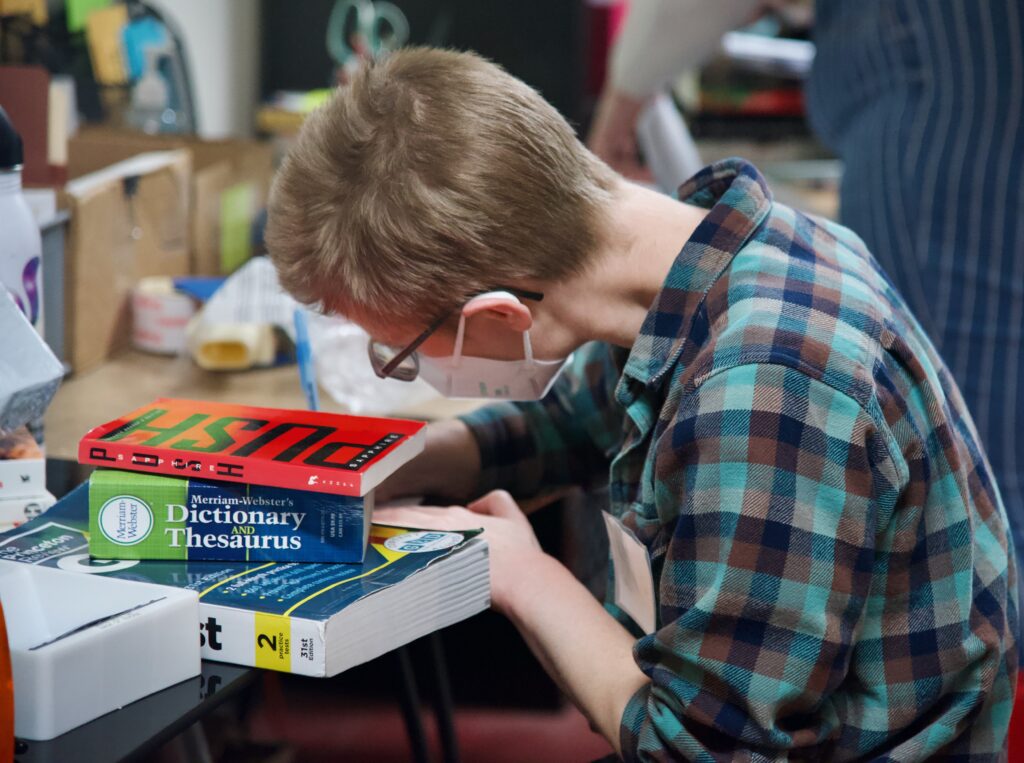 Person leaning over a small stack of books.