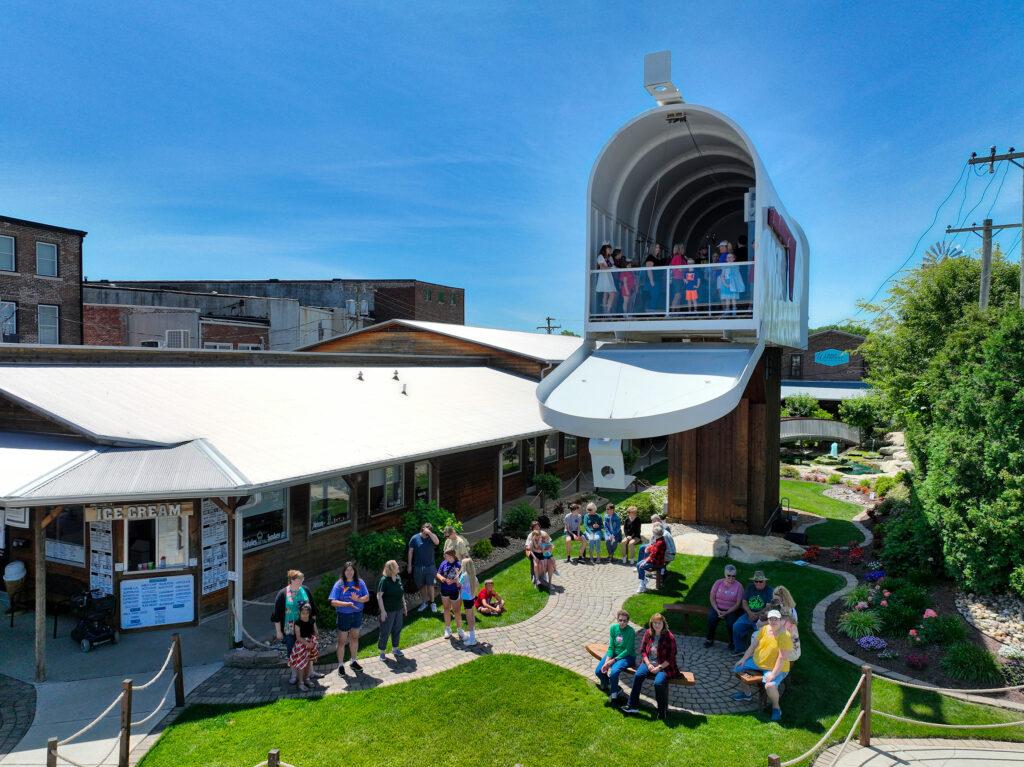 People stand inside a giant mailbox overlooking other people below it.
