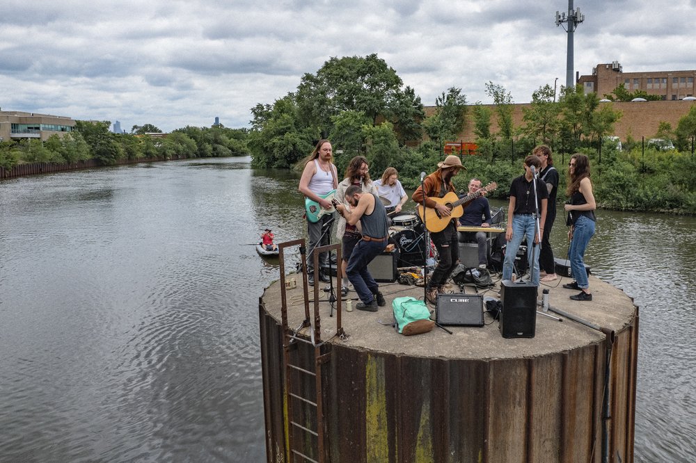 A band on a raised platform in the middle of a river playing music.