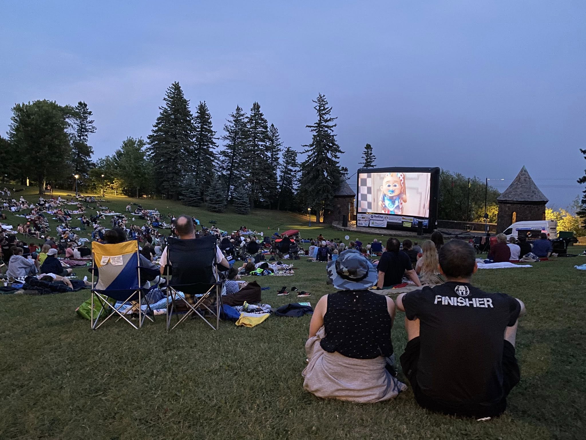 People sit on a hillside watching a movie