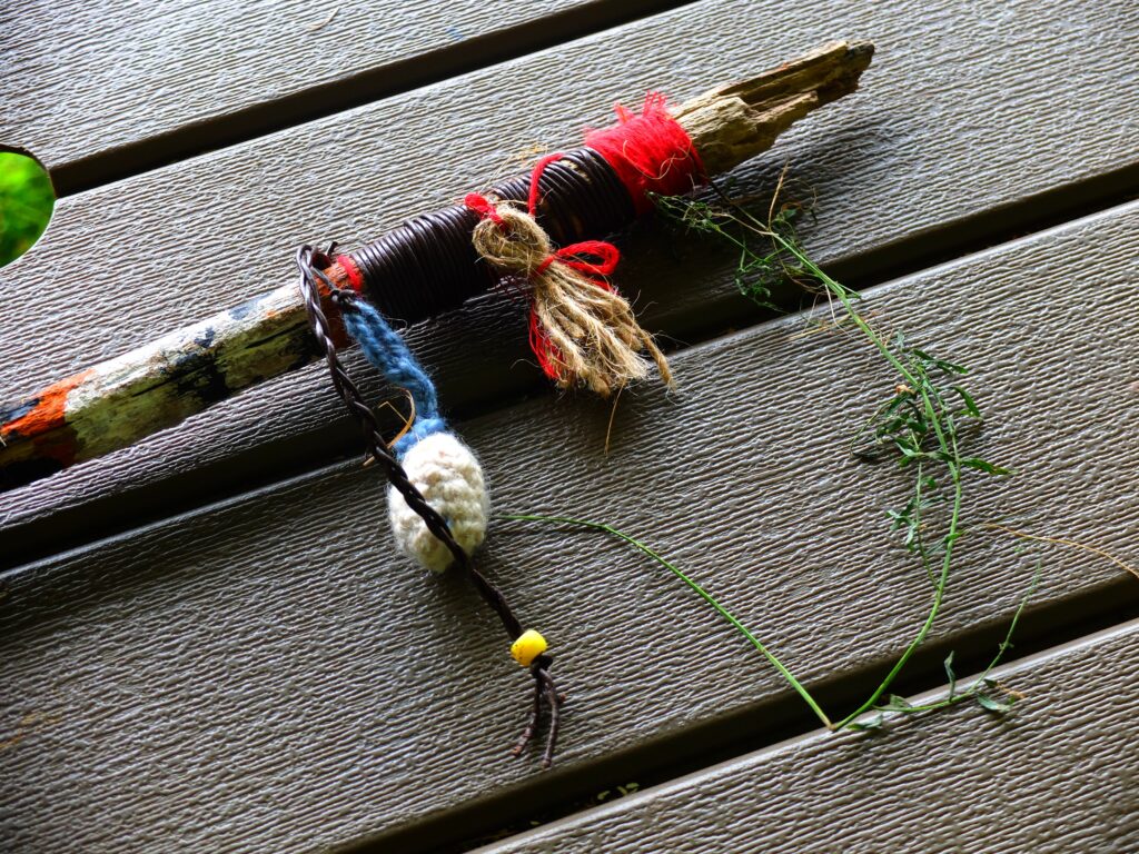 A stick wrapped in yarn on a picnic table.
