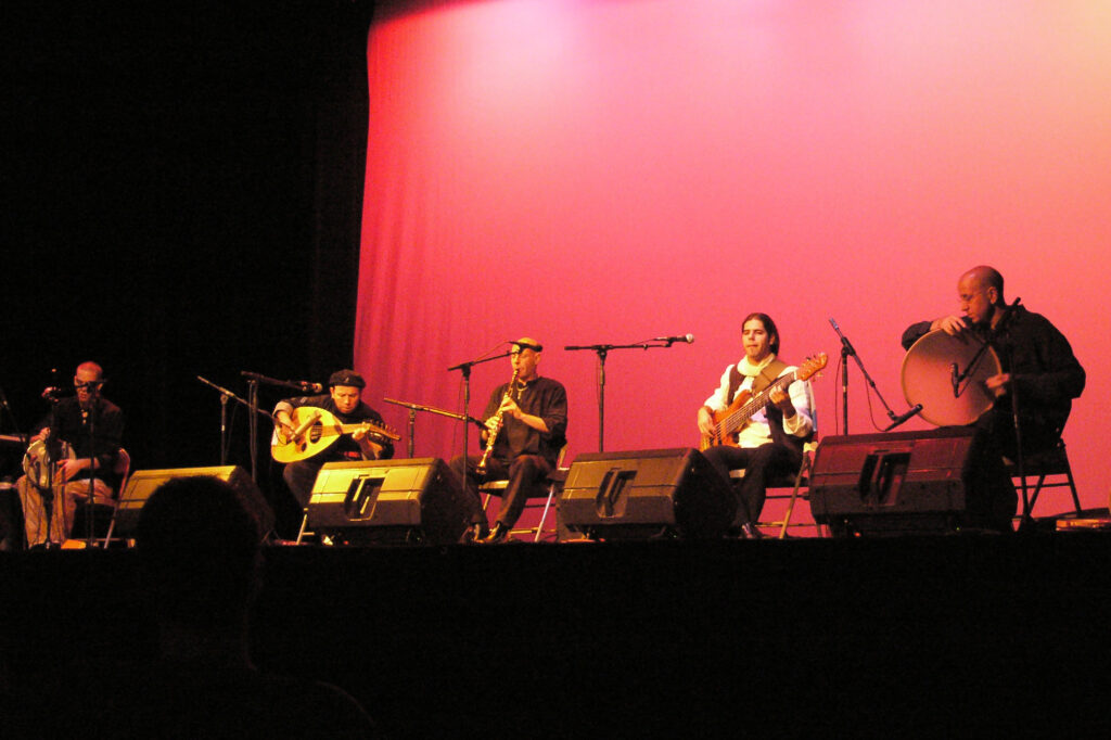 Darma, a band led by world music artist Eyal Sela based in Israel, performs while sitting in a line together on stage.