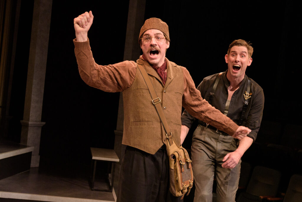 Two actors on stage with expressions of surprise on their faces.