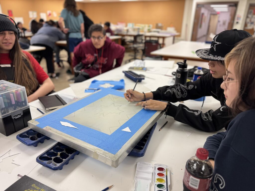 People sit around a table and screenprint.