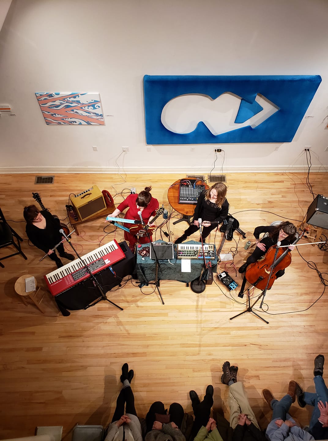 Two flautists, a cellist, and a guitarist on stage with various other instruments and sound equipment.