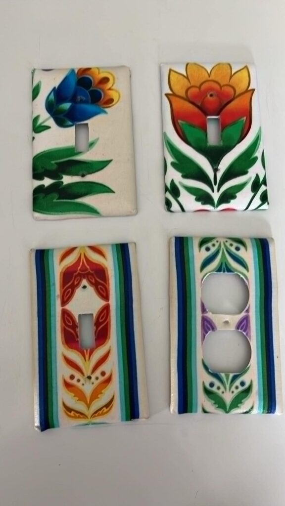 Four outlet and light switch covers adorned with floral paintings.