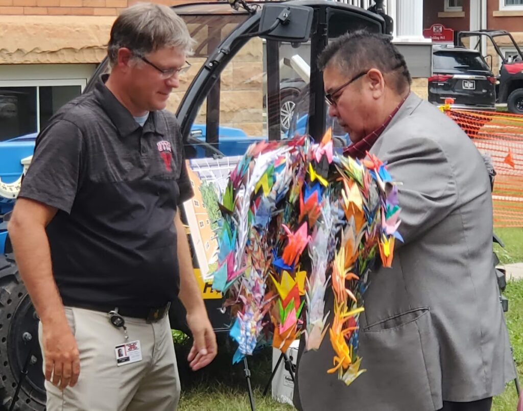 A man in a suit receives a handful of paper cranes