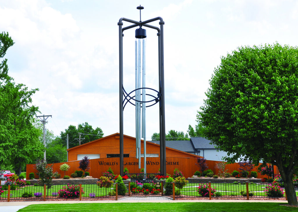 A giant metal wind chime sculpture standing in a park.