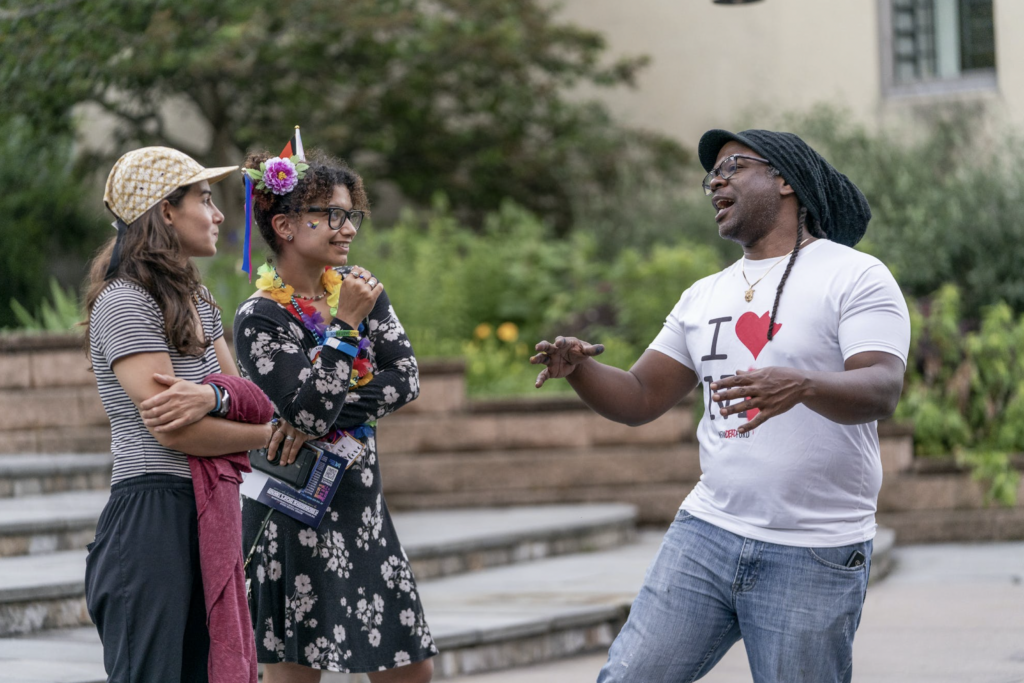 Three people standing outdoors and having a conversation.