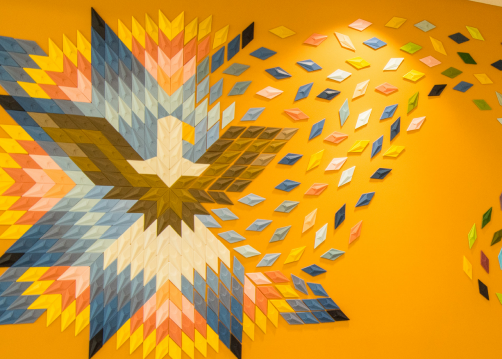 An art piece depicts an eagle and diamonds against a yellow/orange wall.