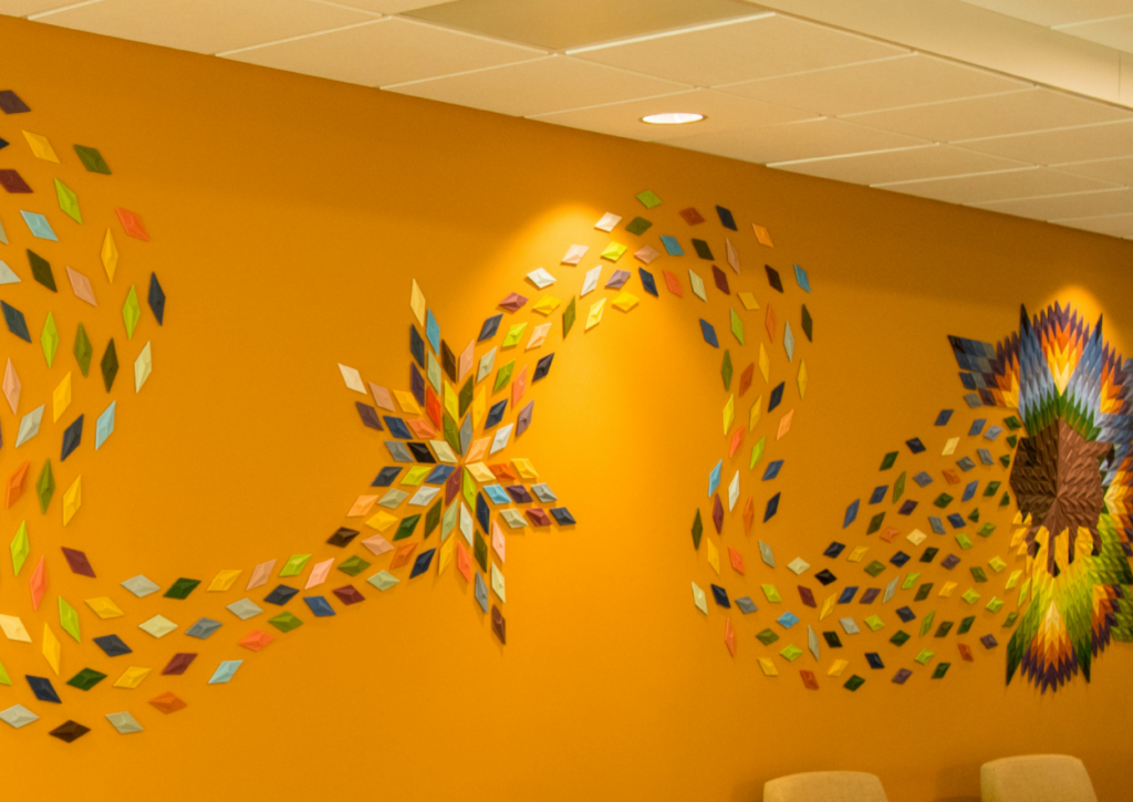 An art piece features 3D diamonds connecting a star and buffalo against a yellow wall.