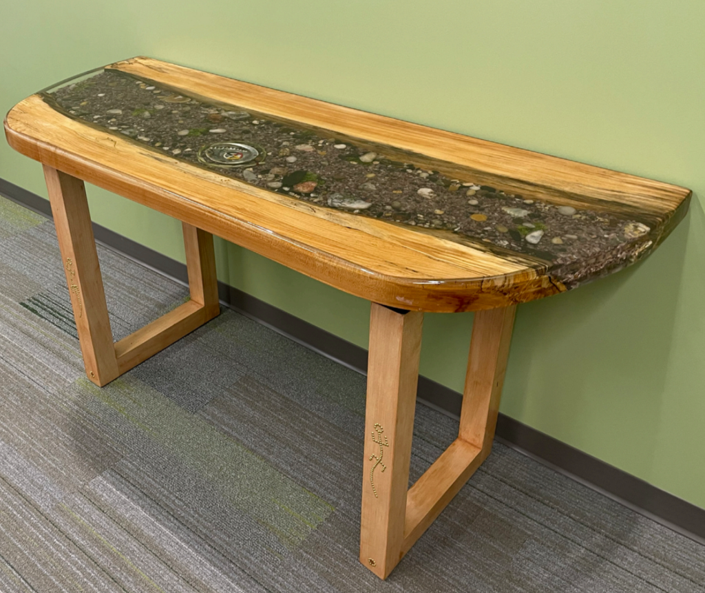 A wooden table with a resin center indoors against a bright green wall.